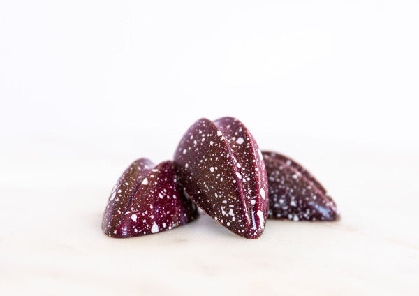 Schoko-Himbeer Praline 
mit roter Kakaobutter geschminkt und weißen Punkten